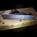 Un machiniste s'occupe de la semelle d'un rabot à la main.