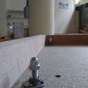 Vis de réglage de la planéité (intérieur de la rallonge).Les têtes des écrous borgnes vont lever/baisser le plateau d'entrée.