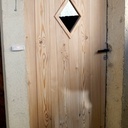 Porte de service en mélèz et ca petite vitre en losange.