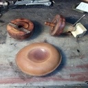 vue démontée: on y voit la marque du fil de fer à gauche, au milieu l'axe de support, et l'etau avec la clé pour fixer le taquet. Et en bas le coussinné en cuir rempli de sable, cousu main, sur lequel on incline l'ensemble pour travailler à l'aise