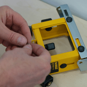 Bouton de réglage en hauteur retiré et préparation de la visserie avant son remontage sur le support DeWALT DE7024.