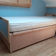 Un lit prêt avec son matelas. On voit les pieds sur lesquels il repose