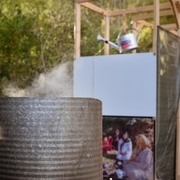 Bidon d’au chauffée avec le robinet pour remplir les arrosoirs, visibles dans le fond de la photo.