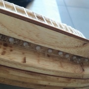 sur le flanc de l'instrument une autre gorge faite à la défonceuse avec la fraise à écrire. Les trous des cordes débouchent sur le plan incliné. Ca permet de "cacher" l'extrémité fixe des cordes avec perle + noeud + une goutte de glu cyanoacrylate.