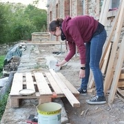 Katharina passe la couche de finition sur les montants, afin qu’ils résistent à l’humidité et au temps.