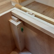 Détail d'un pied de lit, du tasseau en hêtre pour le bloquer, et des coulisses en queue d'aronde des façades