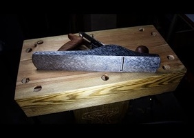 Un machiniste s'occupe de la semelle d'un rabot à la main.