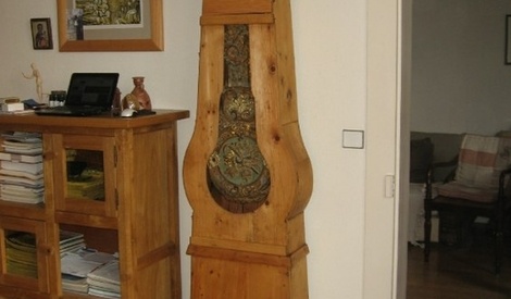 Pendule en forme d'horloge de parquet en métal à décor peint d'une scène galante. Petit cadran