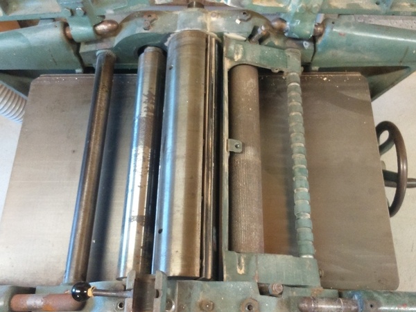 Le système d'arbre et entraîneurs, table de dégauchisseuse relevées (position rabotage)