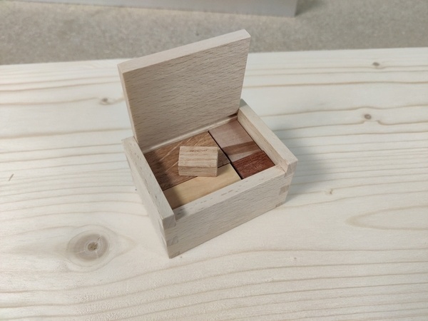 Une boîte remplie de petits sucres en bois, un sucre ne rentre pas