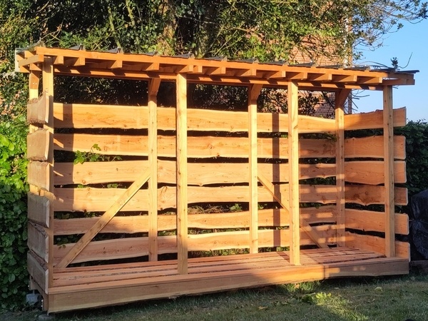 Abri à bois en mélèze terminé avec la lumière du soleil couchant.