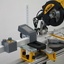 Butée numérique pour scie Pedante installée à gauche d’une scie à onglet DeWALT sur un piétement mobile DeWALT DE7023-XJ.